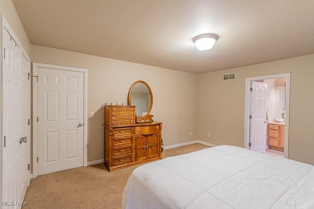 bedroom with ensuite bathroom, light colored carpet, and a closet