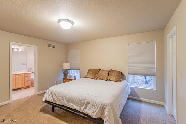 carpeted bedroom with a textured ceiling and connected bathroom