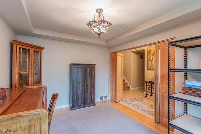 office area featuring a raised ceiling and light hardwood / wood-style flooring