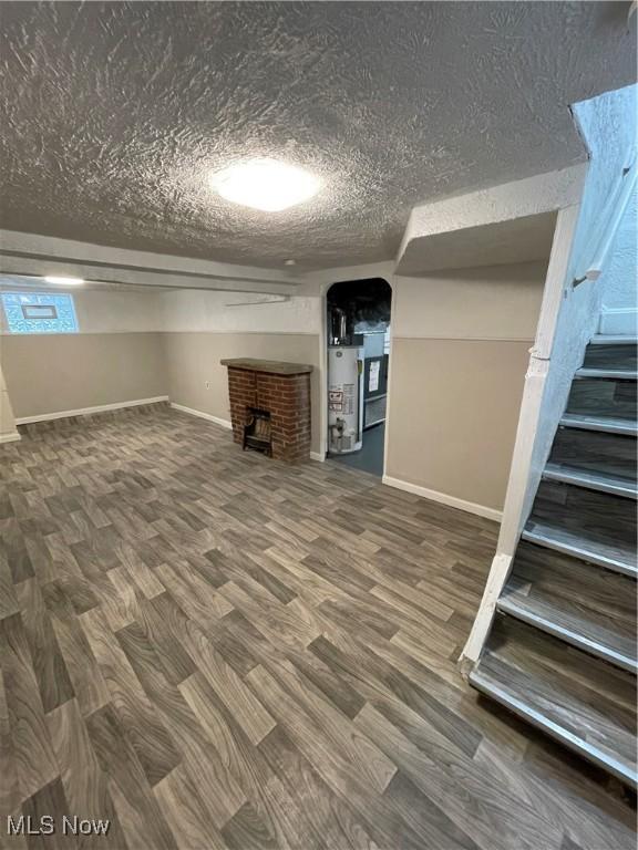 basement featuring water heater, hardwood / wood-style floors, and a brick fireplace