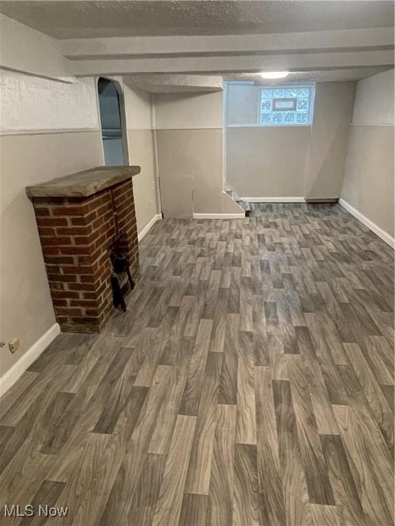 basement featuring dark hardwood / wood-style floors and a brick fireplace