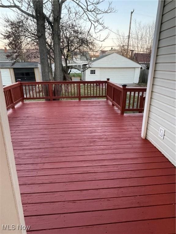 deck at dusk featuring a garage and an outdoor structure