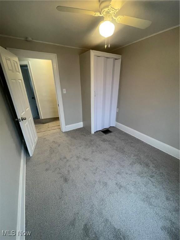 unfurnished bedroom featuring ceiling fan, crown molding, and light colored carpet