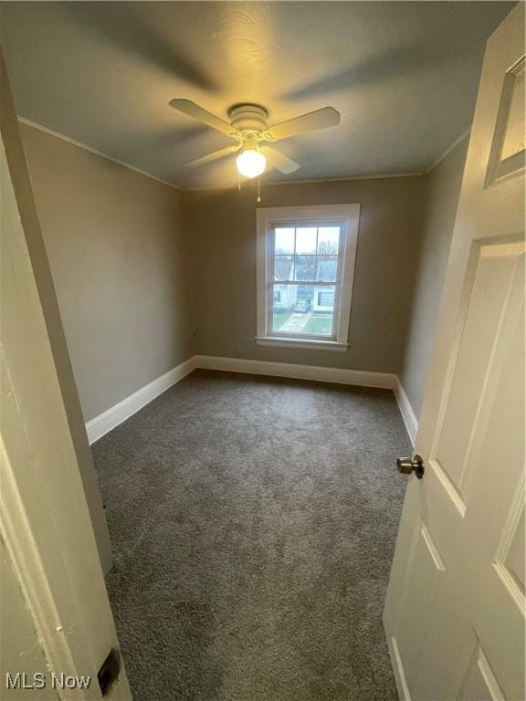 empty room with ceiling fan and dark carpet