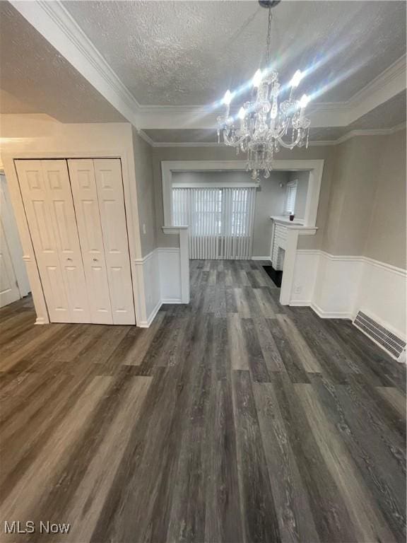 unfurnished dining area featuring a notable chandelier, dark hardwood / wood-style flooring, a textured ceiling, and crown molding