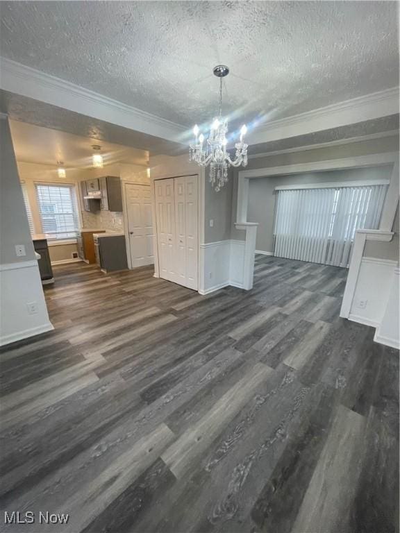 unfurnished dining area featuring a notable chandelier, dark hardwood / wood-style floors, ornamental molding, and a textured ceiling