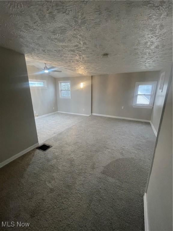 basement featuring carpet flooring, a textured ceiling, and plenty of natural light