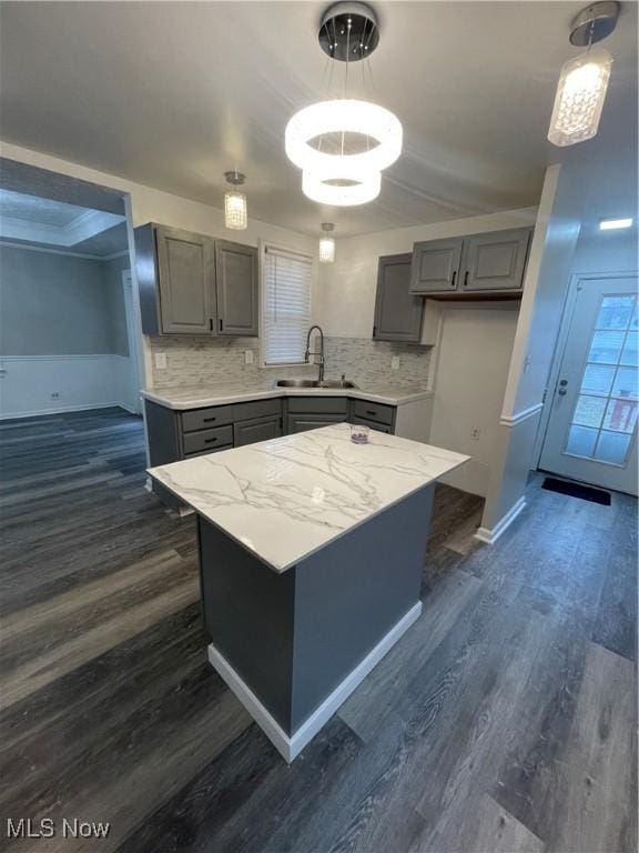 kitchen featuring tasteful backsplash, sink, a center island, dark hardwood / wood-style floors, and hanging light fixtures