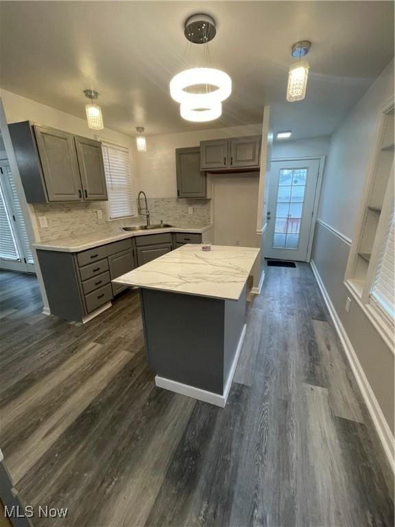 kitchen featuring gray cabinetry, a center island, sink, decorative backsplash, and decorative light fixtures