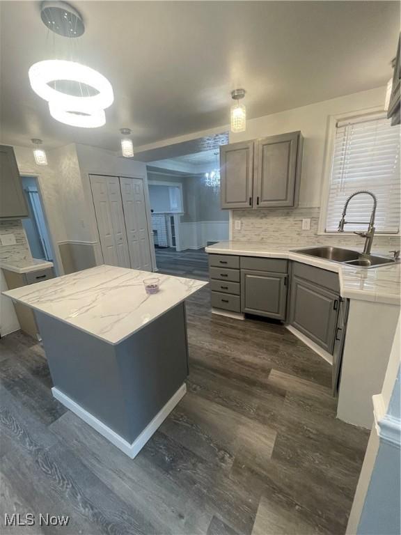 kitchen with gray cabinetry, a center island, dark wood-type flooring, sink, and decorative backsplash