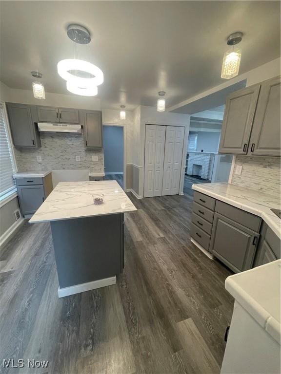 kitchen with dark hardwood / wood-style floors, a kitchen island, hanging light fixtures, and gray cabinetry