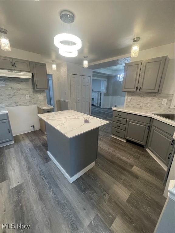 kitchen featuring sink, dark hardwood / wood-style floors, gray cabinets, decorative backsplash, and a kitchen island