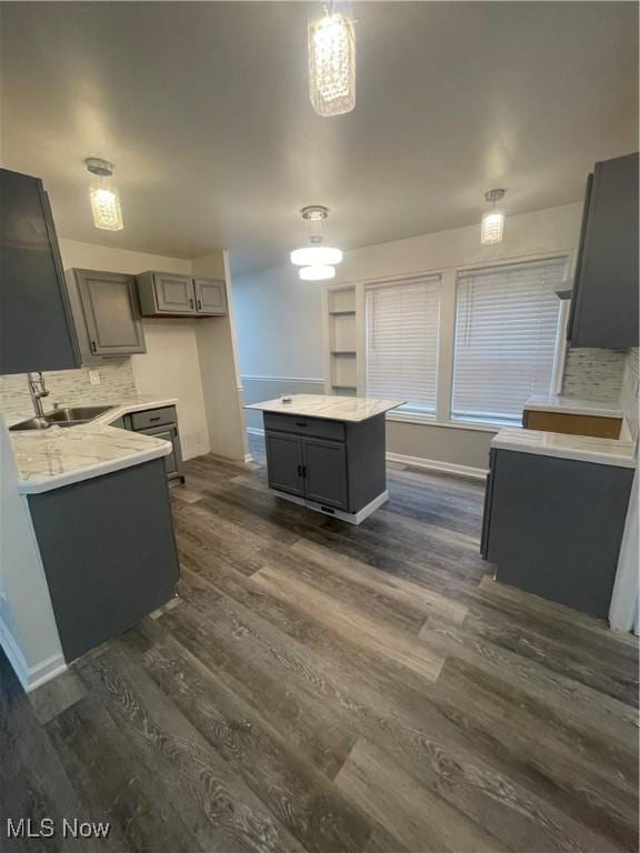 kitchen with decorative light fixtures, dark hardwood / wood-style flooring, gray cabinets, and sink