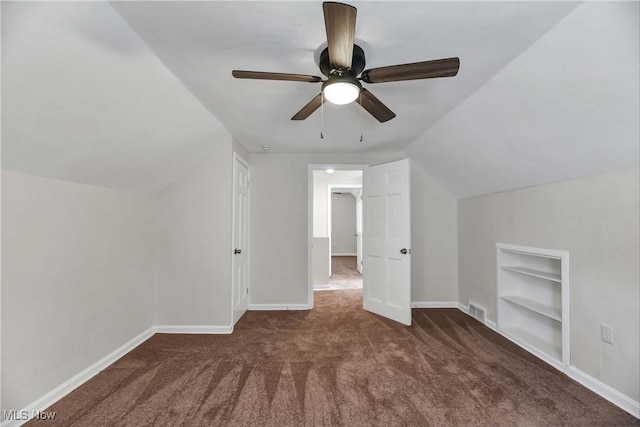 bonus room featuring dark colored carpet, ceiling fan, built in features, and vaulted ceiling