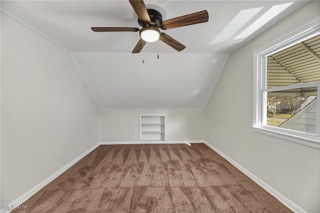 additional living space with built in shelves, ceiling fan, carpet floors, and vaulted ceiling