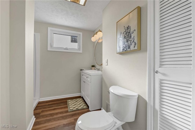 bathroom with hardwood / wood-style flooring, vanity, toilet, and a textured ceiling