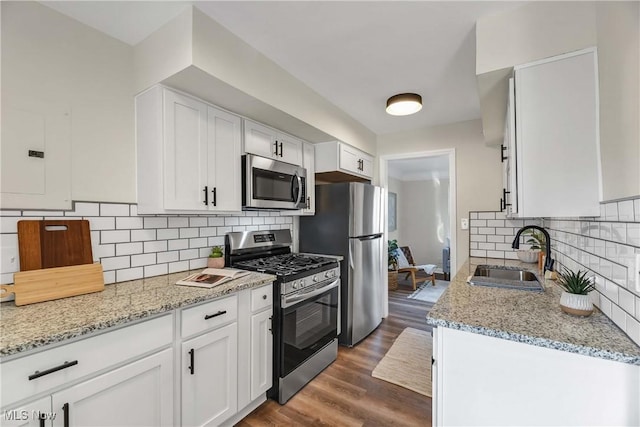 kitchen with white cabinets, light stone counters, sink, and stainless steel appliances