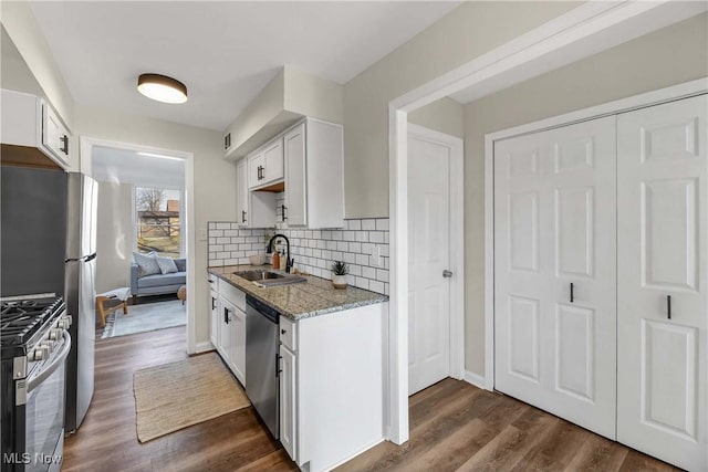 kitchen featuring light stone countertops, appliances with stainless steel finishes, dark wood-type flooring, sink, and white cabinets