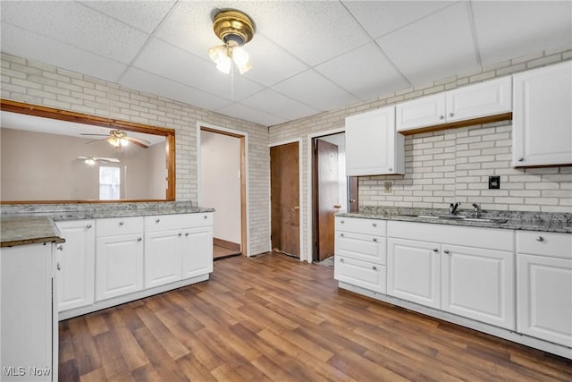 kitchen featuring a paneled ceiling, wood-type flooring, white cabinetry, and sink