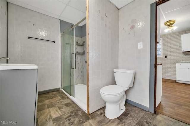 bathroom featuring a paneled ceiling, vanity, toilet, and an enclosed shower