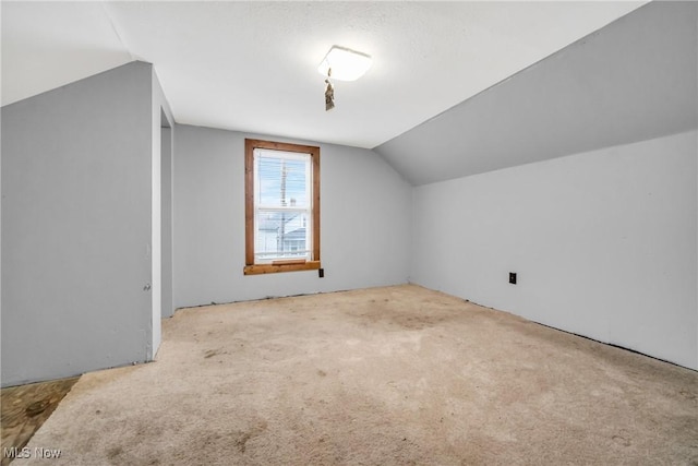 additional living space featuring light carpet and vaulted ceiling