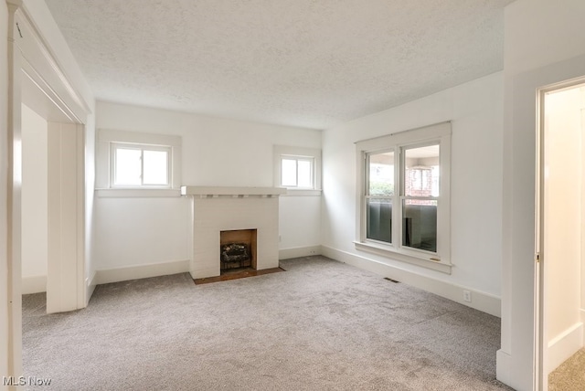 unfurnished living room featuring a textured ceiling and light carpet