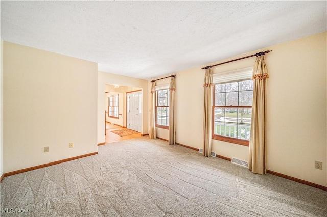 unfurnished room with light colored carpet and a textured ceiling