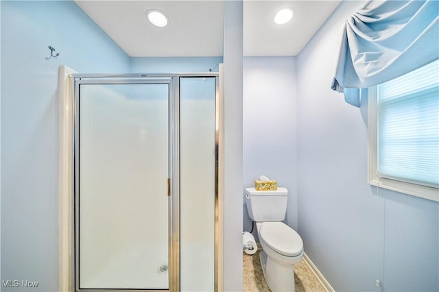 bathroom featuring a shower with shower door and toilet