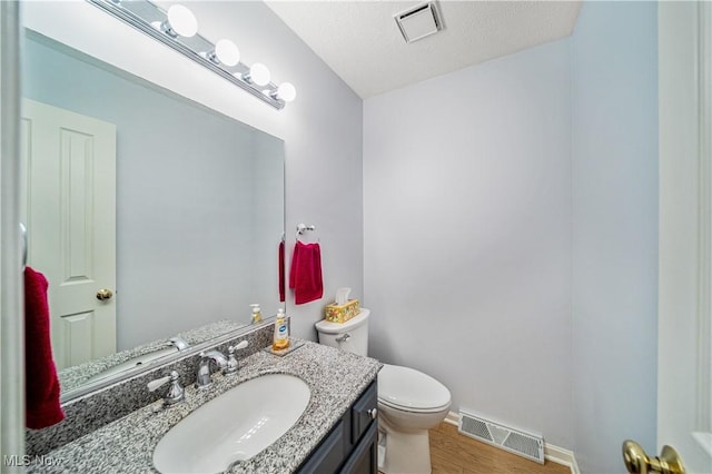 bathroom with hardwood / wood-style floors, vanity, a textured ceiling, and toilet