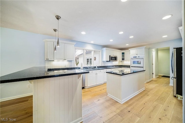 kitchen featuring pendant lighting, light hardwood / wood-style floors, white cabinetry, and stainless steel appliances