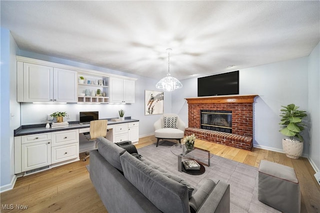 living room with light hardwood / wood-style floors, built in desk, and a fireplace