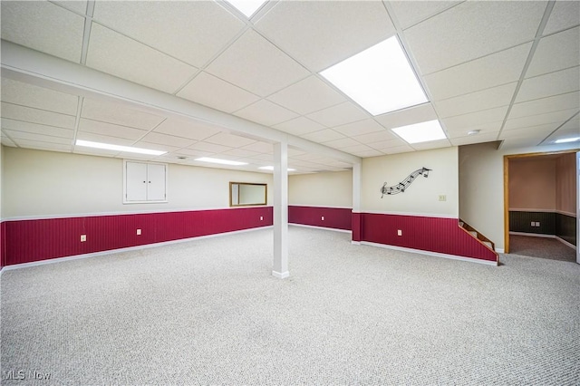 basement with a paneled ceiling and carpet