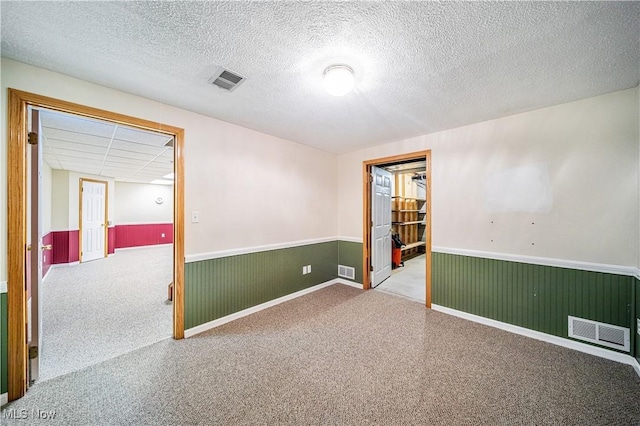 unfurnished room featuring a textured ceiling and wooden walls