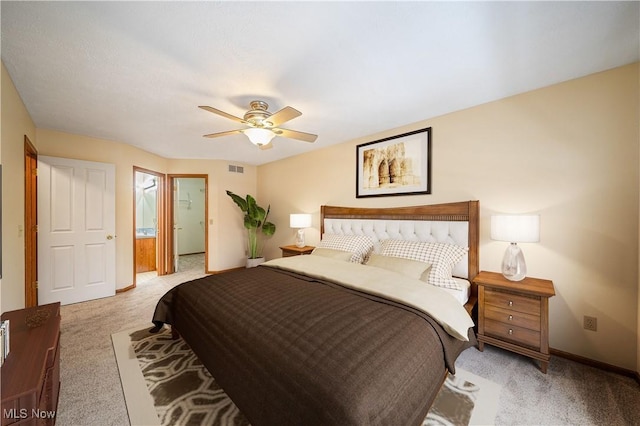 bedroom featuring ceiling fan, light colored carpet, and ensuite bath