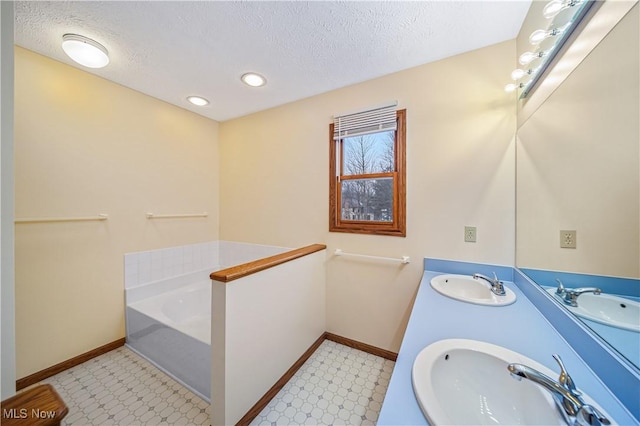 bathroom featuring a textured ceiling, vanity, and a tub