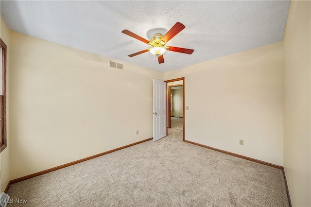 spare room featuring light carpet, a textured ceiling, and ceiling fan