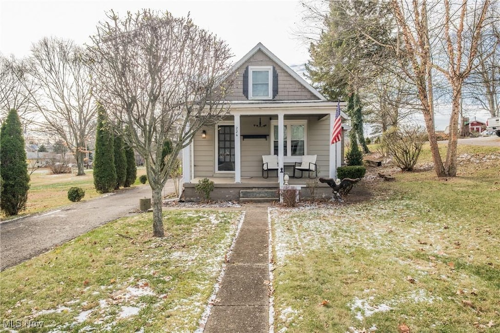 bungalow-style house featuring covered porch and a front lawn