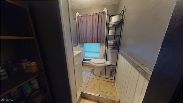 bathroom with tile patterned flooring, toilet, and a textured ceiling