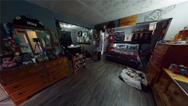 bedroom with dark hardwood / wood-style floors and a textured ceiling