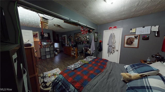 bedroom featuring dark hardwood / wood-style flooring, a textured ceiling, and a closet