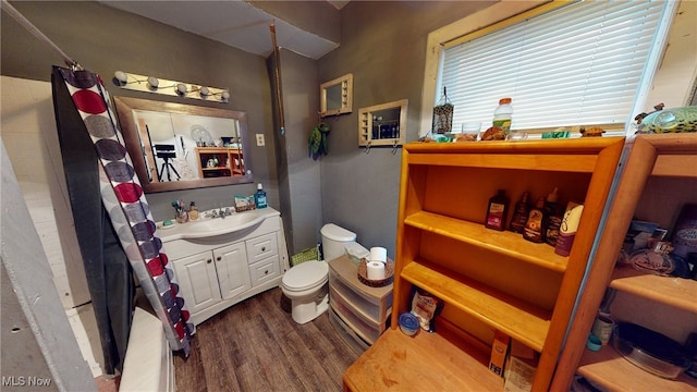 bathroom featuring a shower with shower curtain, hardwood / wood-style floors, vanity, and toilet