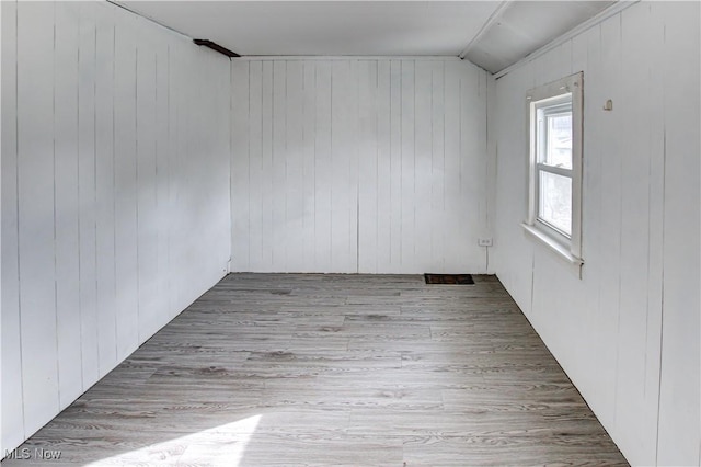 empty room with wood-type flooring and wooden walls