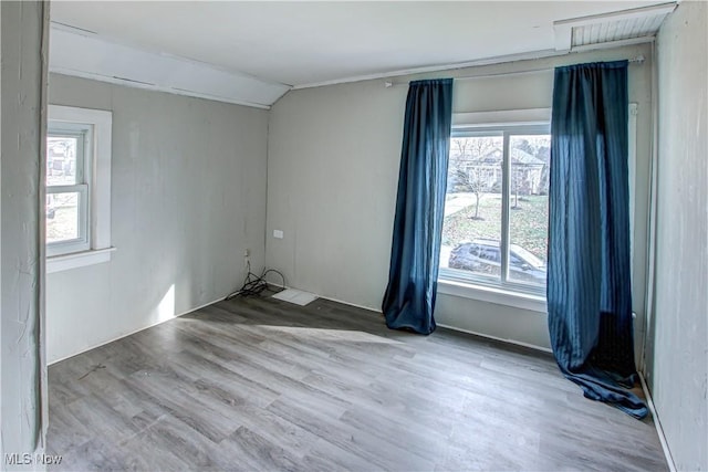 unfurnished room with light hardwood / wood-style floors and lofted ceiling