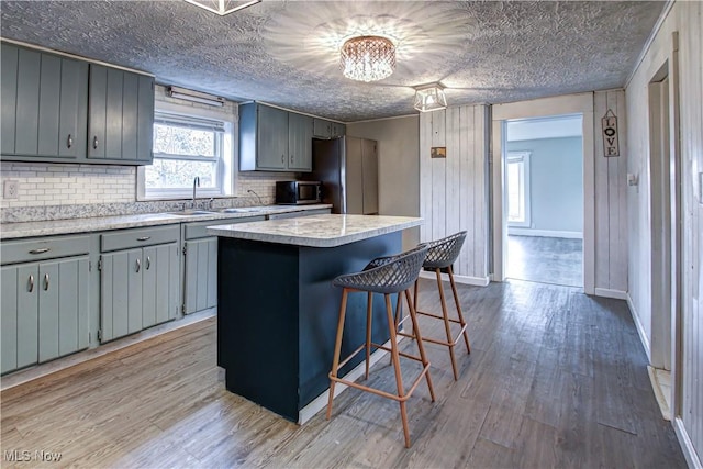 kitchen featuring appliances with stainless steel finishes, light wood-type flooring, sink, a center island, and gray cabinets