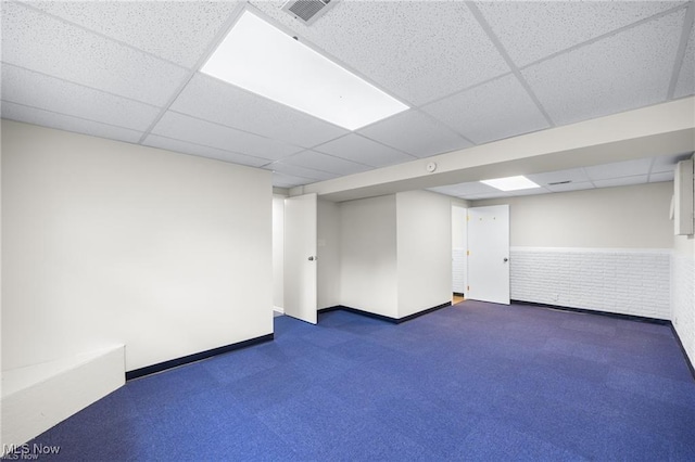 basement with a drop ceiling and brick wall