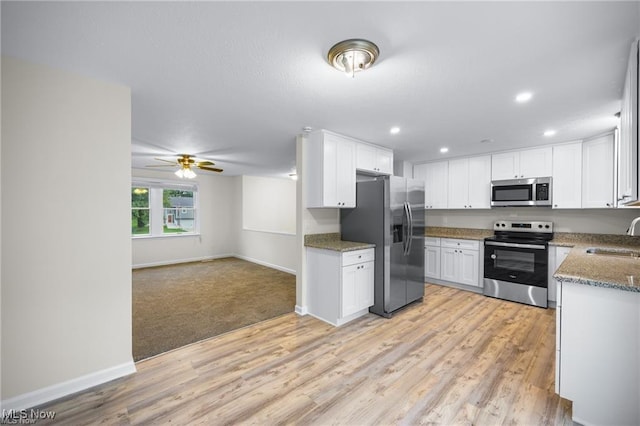 kitchen featuring white cabinets, sink, light stone countertops, light hardwood / wood-style floors, and stainless steel appliances