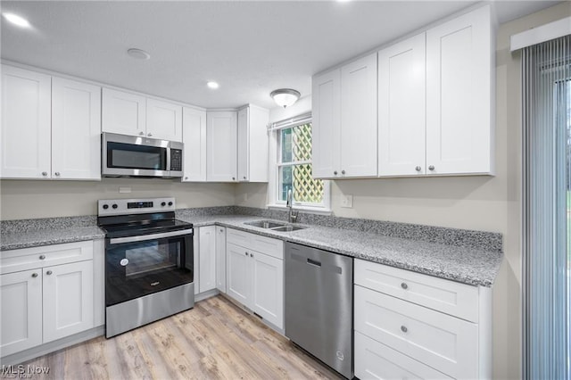 kitchen with sink, white cabinets, light hardwood / wood-style floors, and appliances with stainless steel finishes