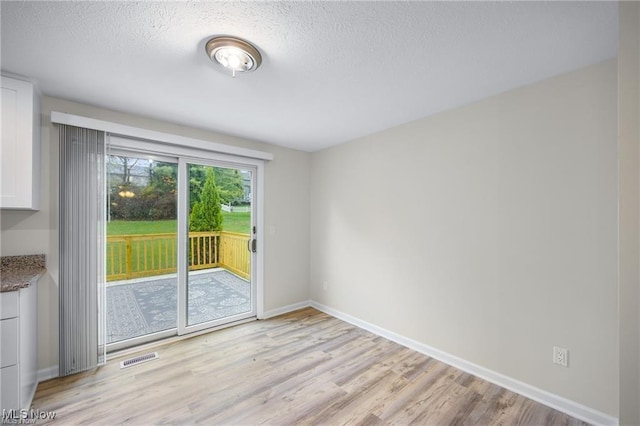 empty room featuring a textured ceiling and light wood-type flooring