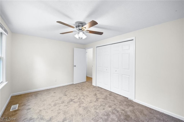 unfurnished bedroom with ceiling fan, a closet, and light carpet