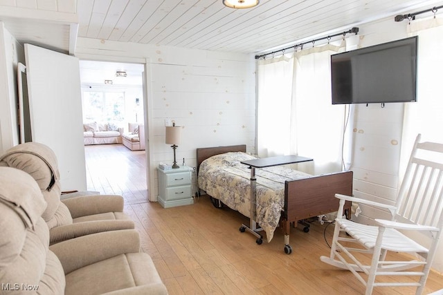 bedroom featuring light hardwood / wood-style floors, wooden walls, and wood ceiling